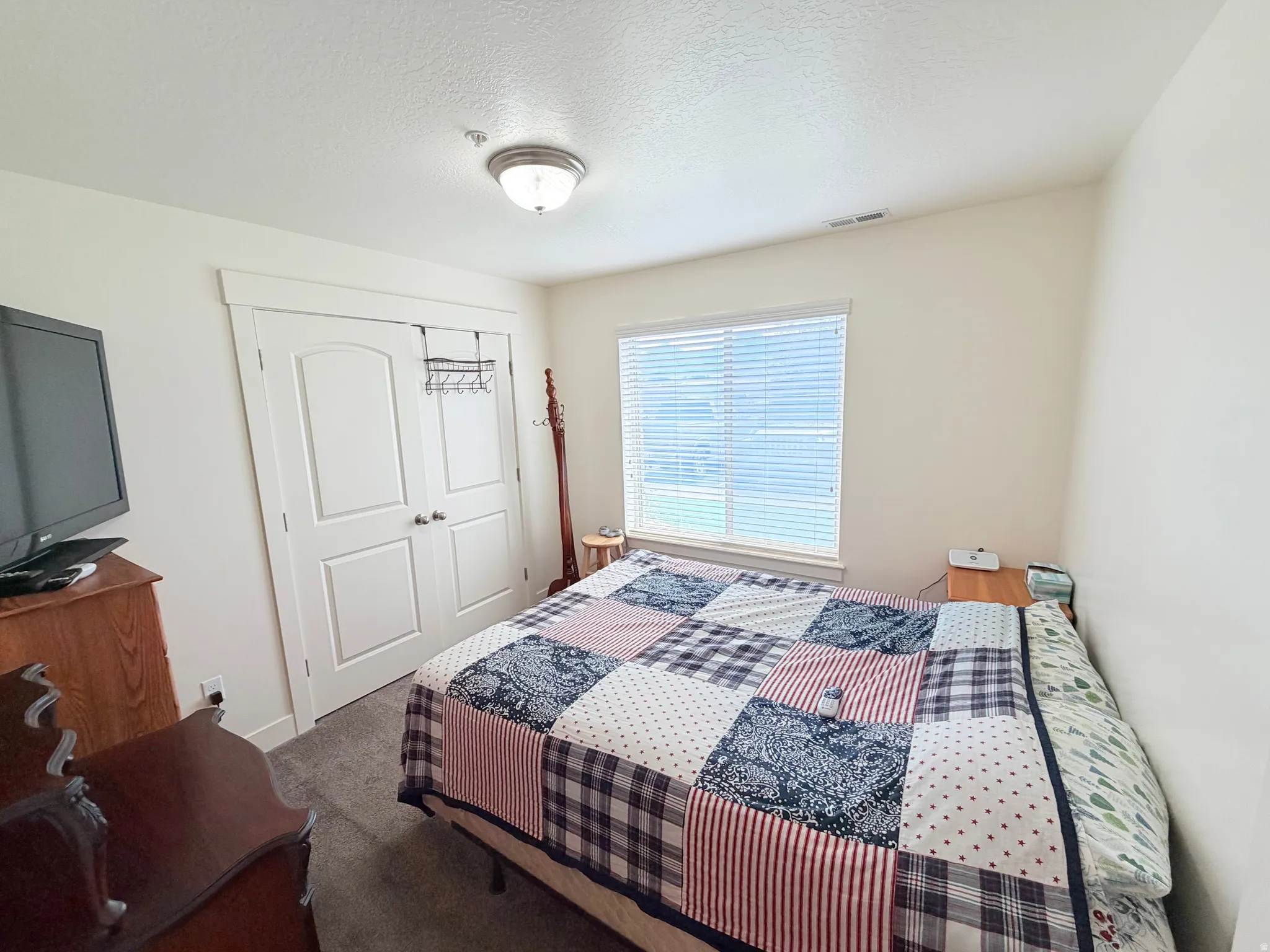 Bedroom featuring neutral wall paint, a window with blinds, and white bi-fold closet doors with arched panels