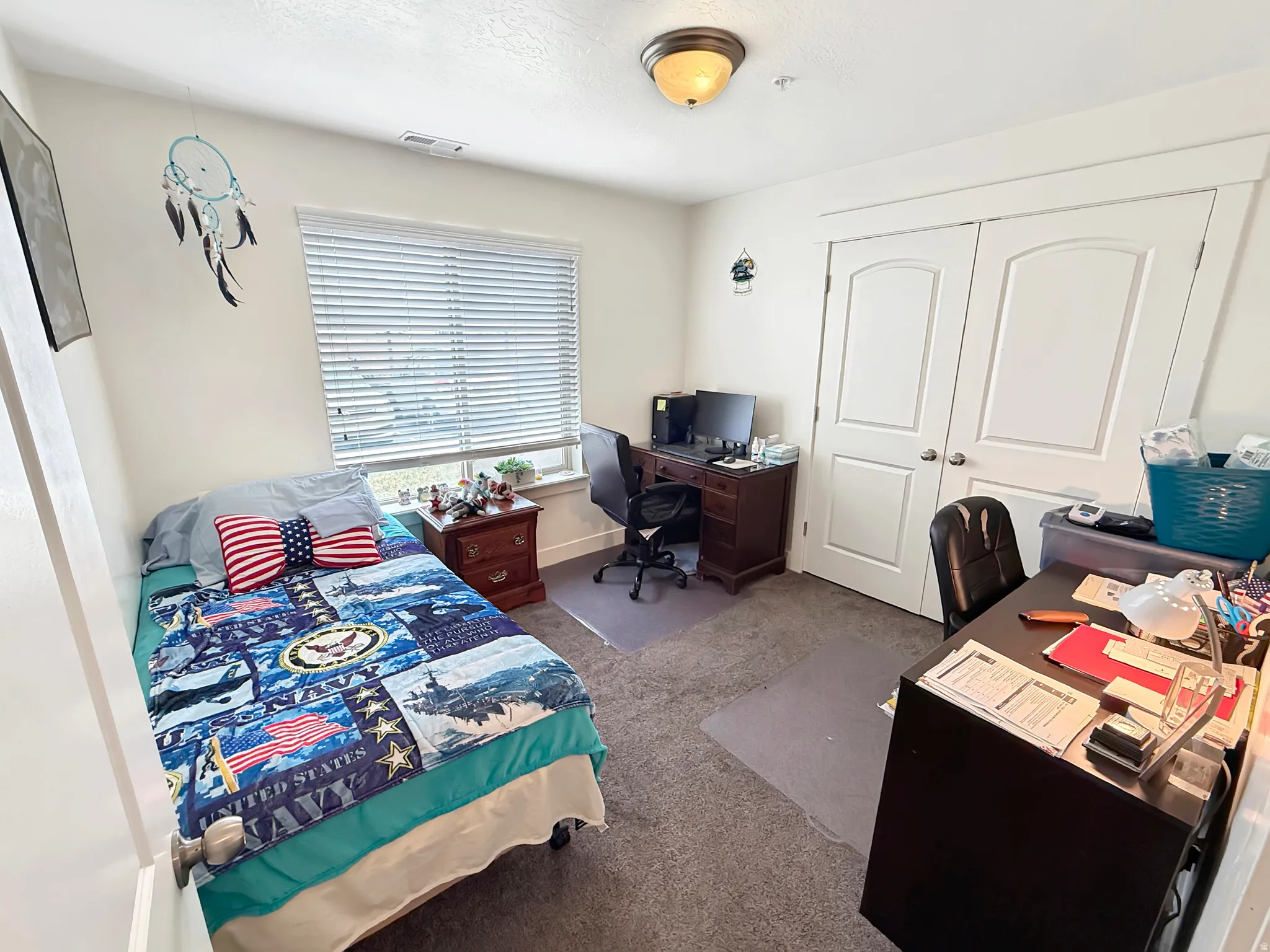 Bedroom featuring an office area, dark carpet, and a closet