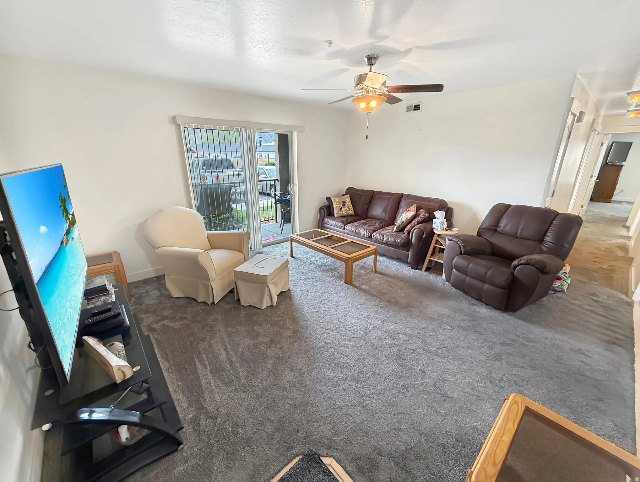 Living area with ceiling fan and carpet flooring