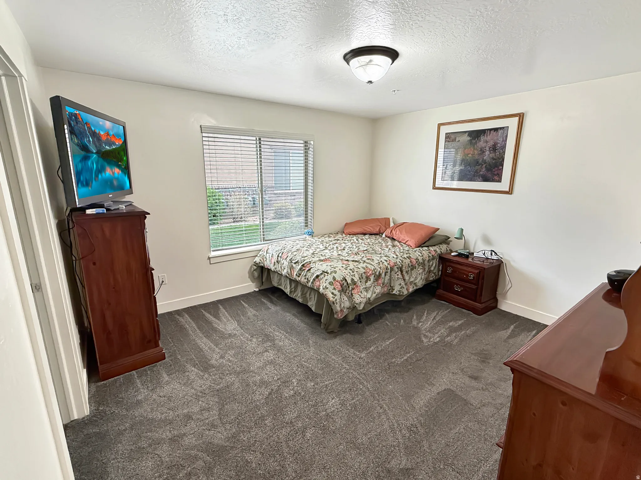 Bedroom with dark carpet and a textured ceiling