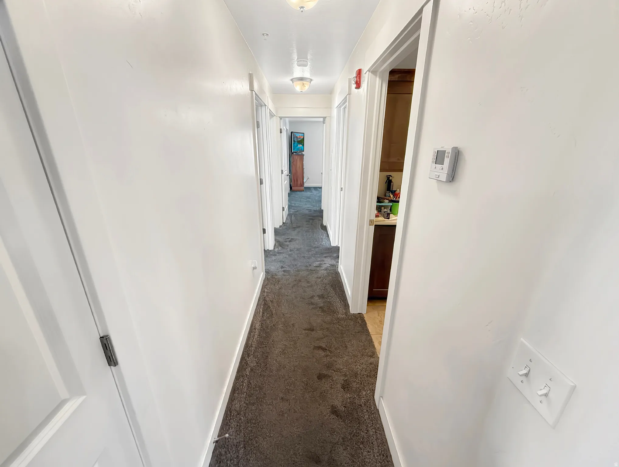 Hallway featuring light colored carpet and baseboards