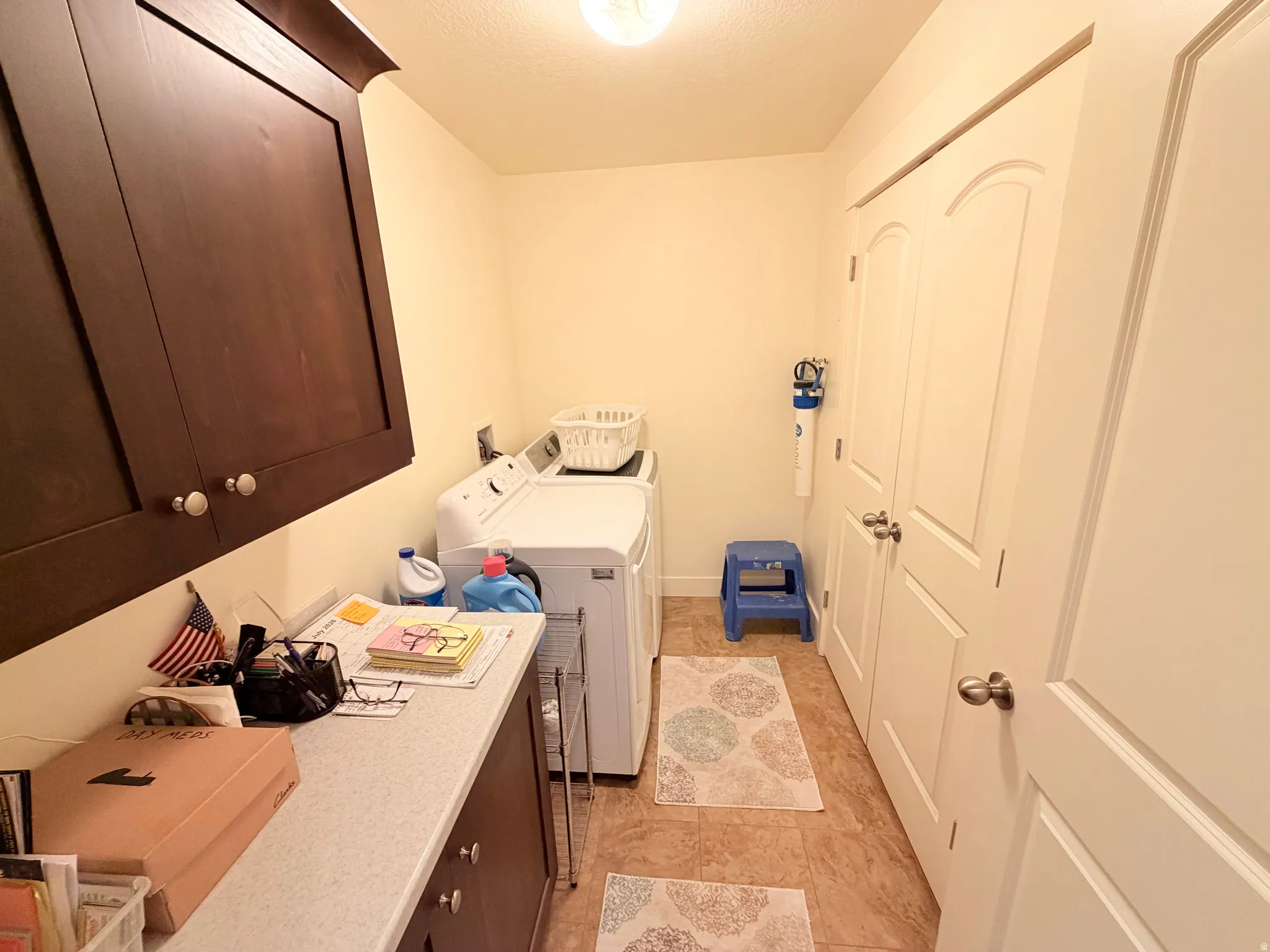 Laundry area featuring dark wood-finish cabinetry, a light-colored countertop, and two white panel doors