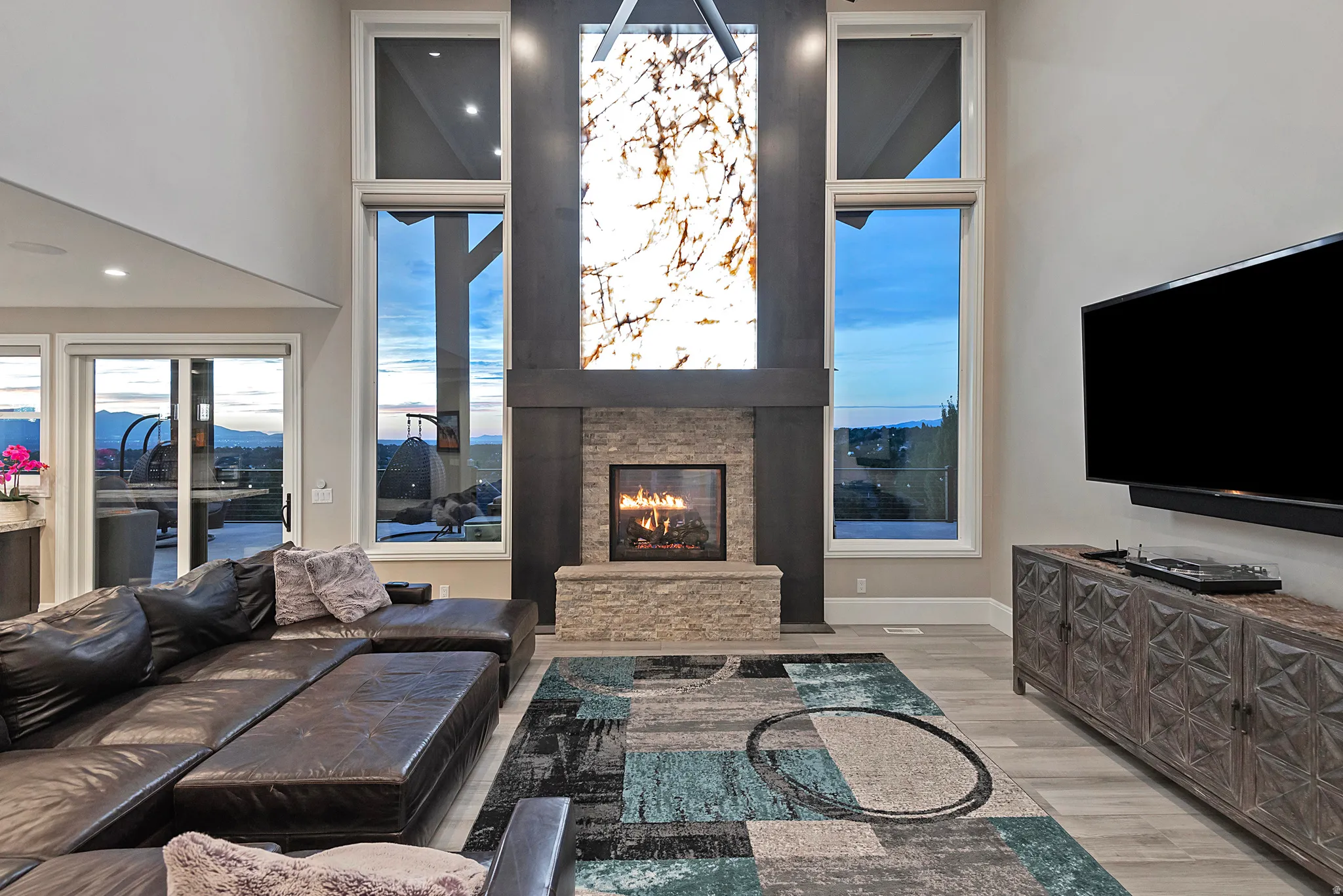 Living area with light wood-style floors, a fireplace, a high ceiling, and a mountain view