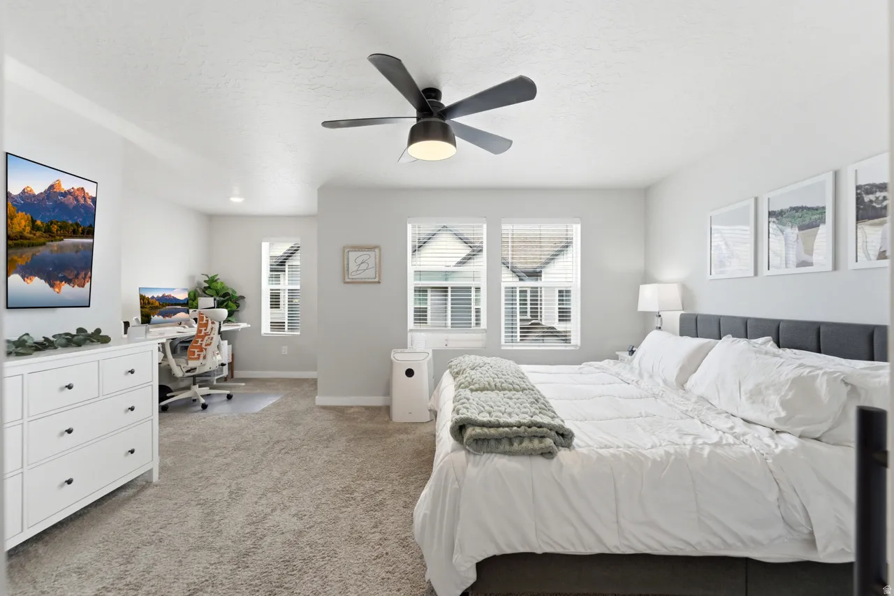 Bedroom featuring a desk, light carpet, a ceiling fan, and a textured ceiling