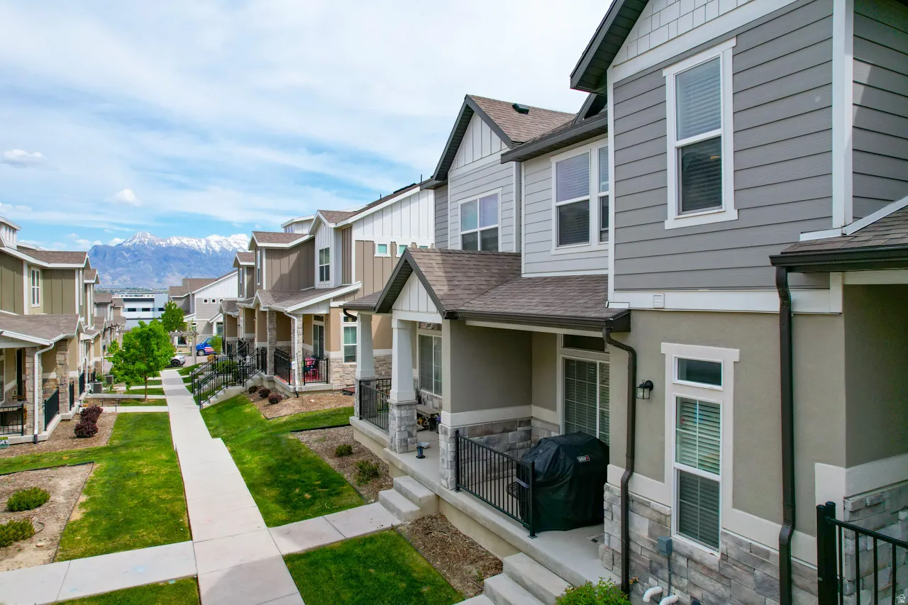 View of side of home featuring stone siding, a shingled roof, a mountain view, a residential view, and covered porch
