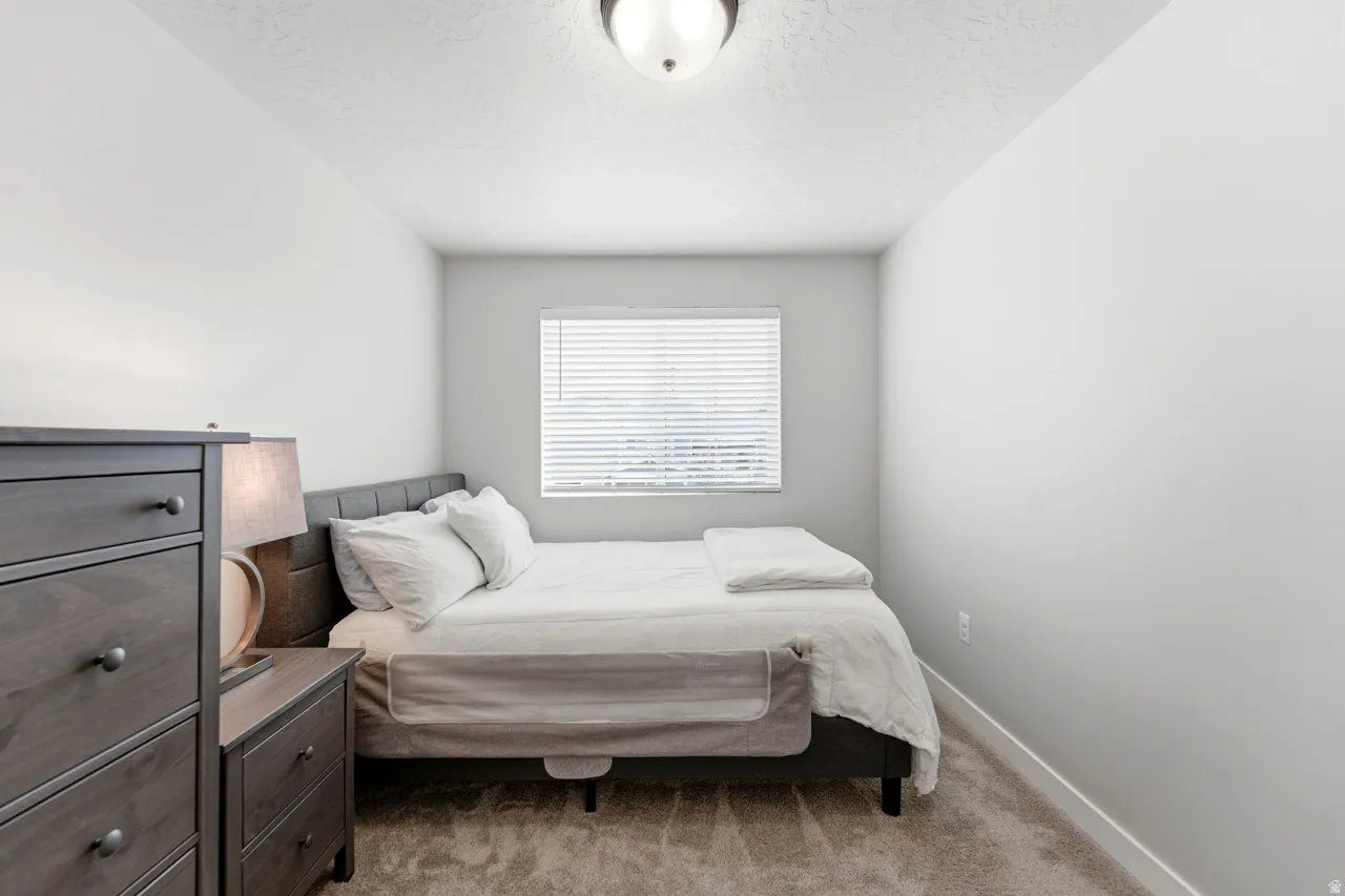 Carpeted bedroom featuring baseboards and a textured ceiling