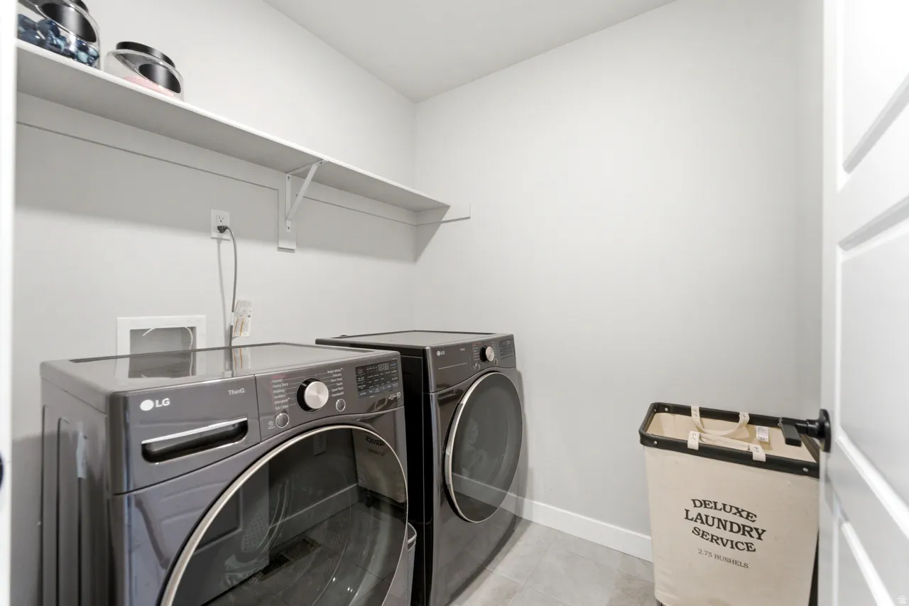 Laundry area featuring washing machine and clothes dryer and light tile patterned floors