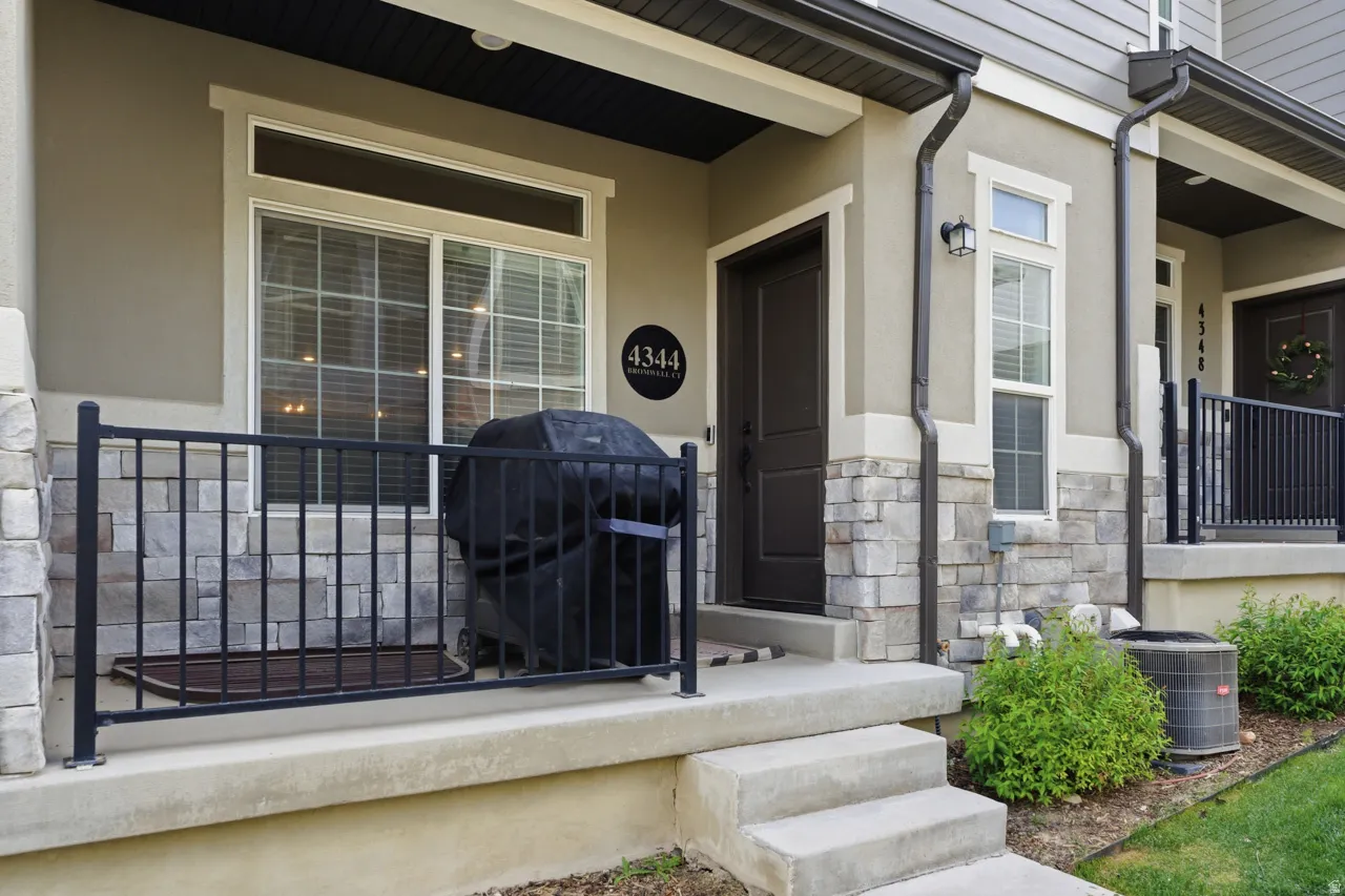 Doorway to property with stucco siding, stone siding, and covered porch