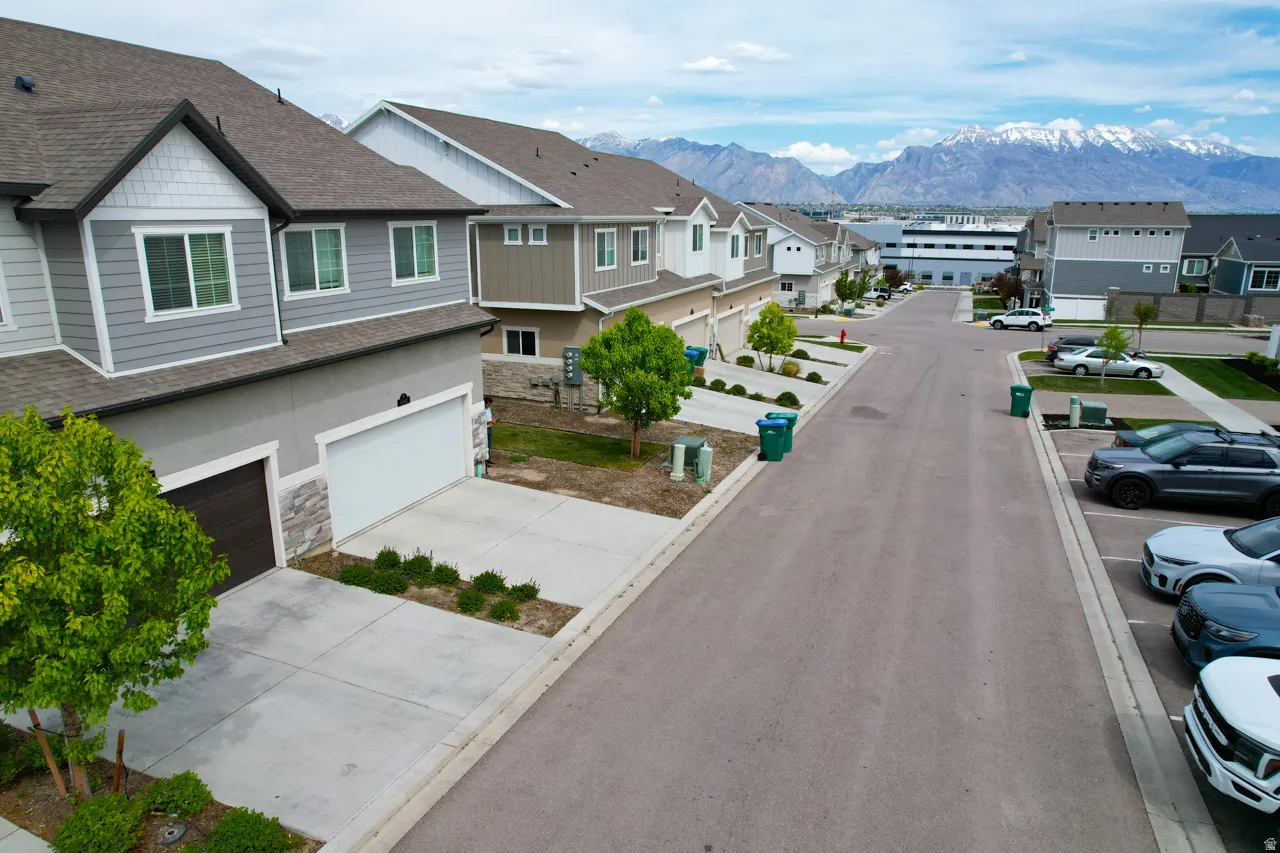 View of asphalt street with a residential view, a mountain view, and curbs