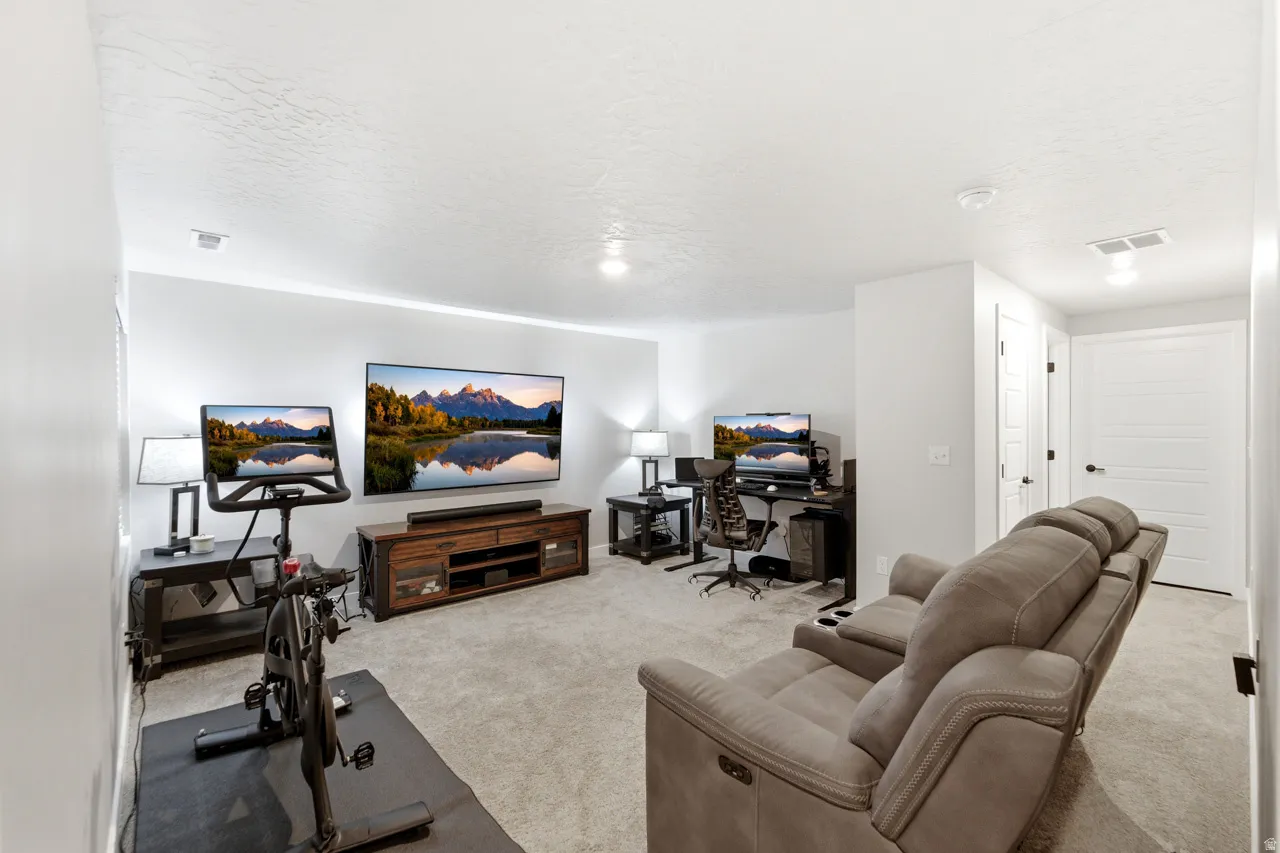 Living area featuring light carpet, a textured ceiling, and a desk