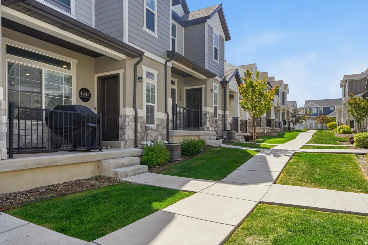 View of exterior entry with a porch, a residential view, a lawn, and stone siding