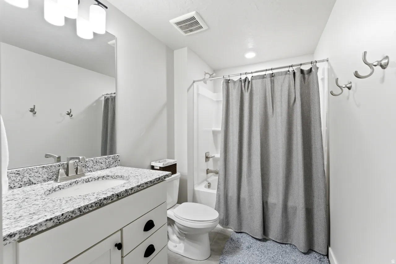 Bathroom with vanity, shower / bath combo with shower curtain, and light tile patterned floors