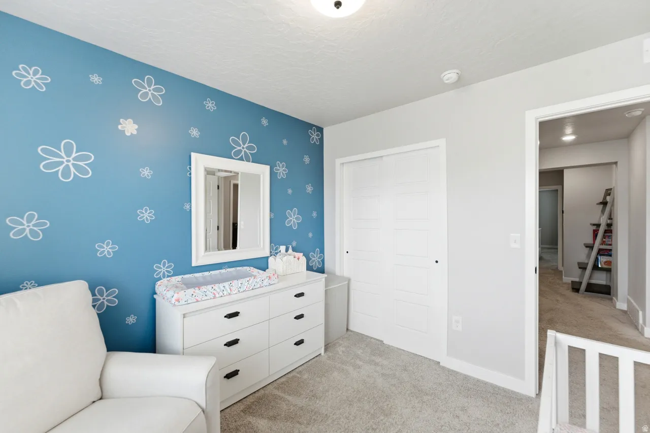 Bedroom with light carpet, a closet, and a textured ceiling