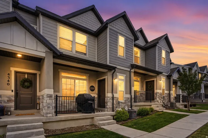 Craftsman-style home with stone siding and a porch. AI enhanced twilight photo.