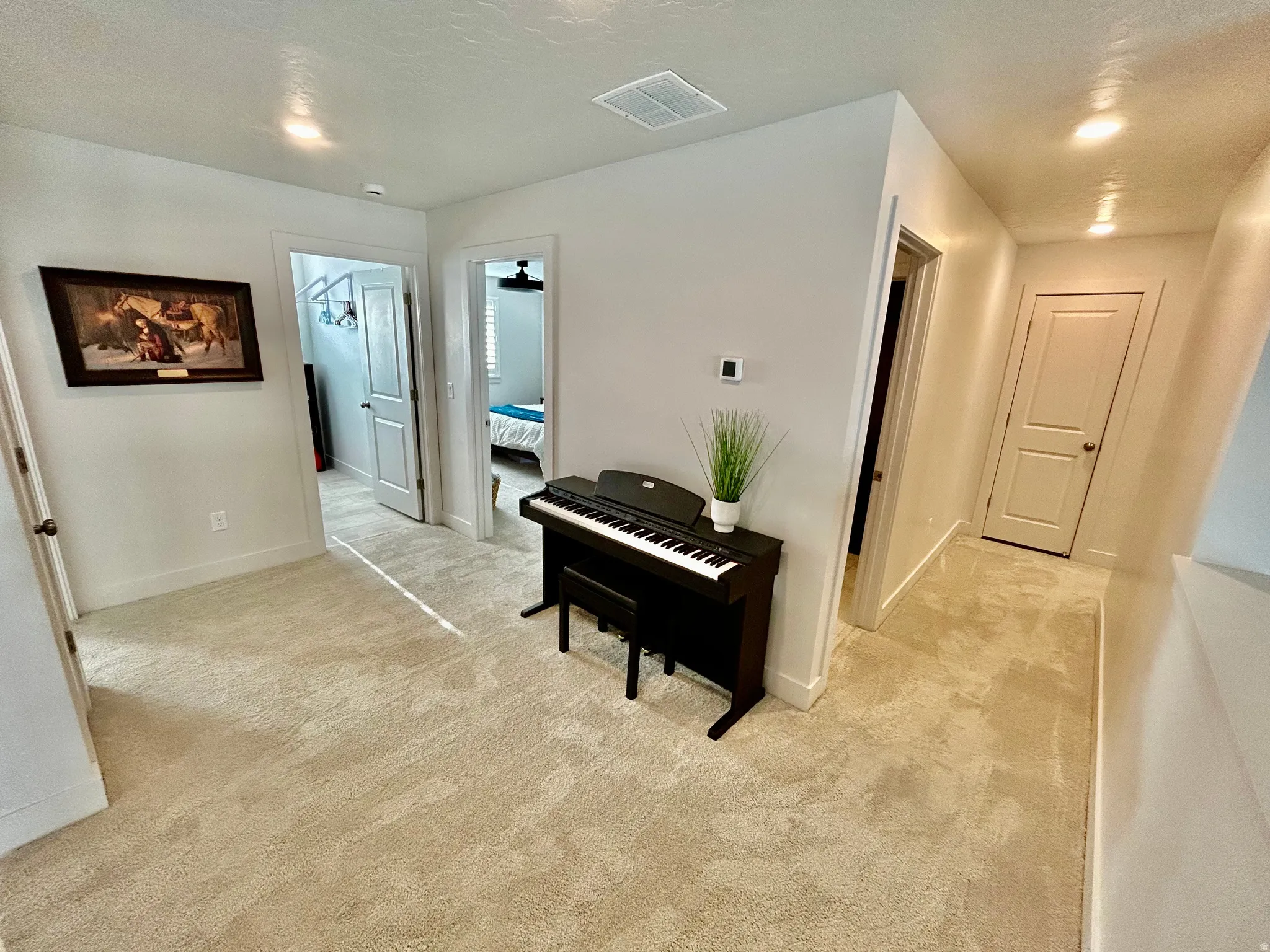 Hall with light colored carpet and recessed lighting