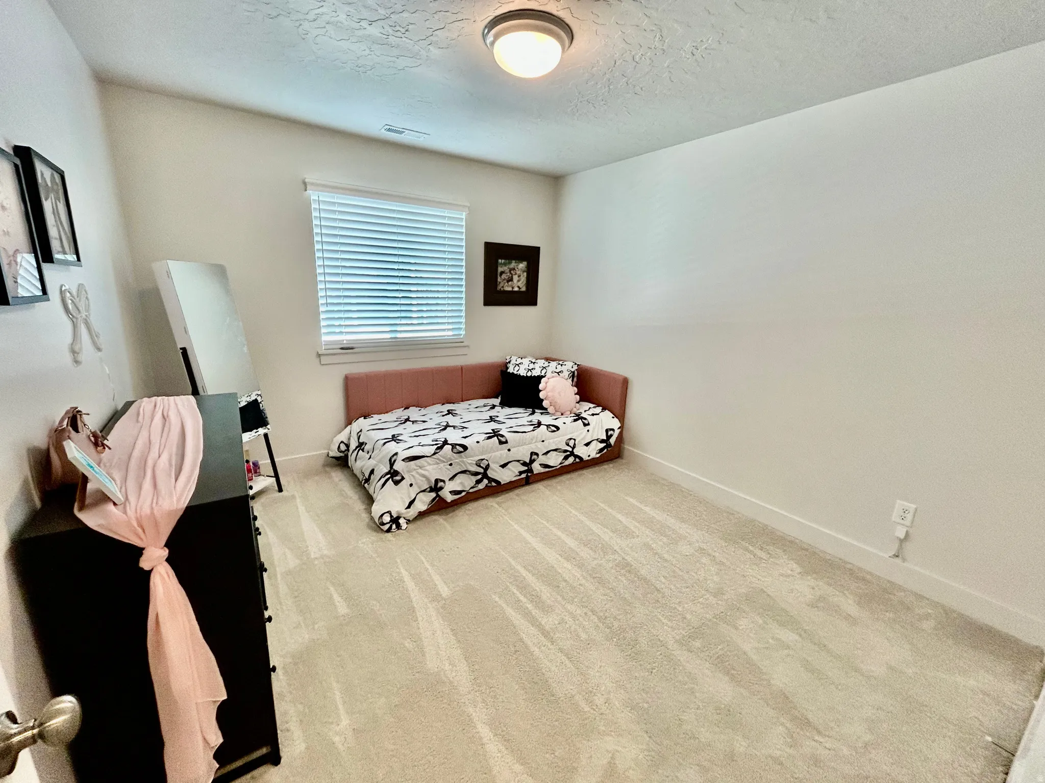 Bedroom featuring light colored carpet and a textured ceiling