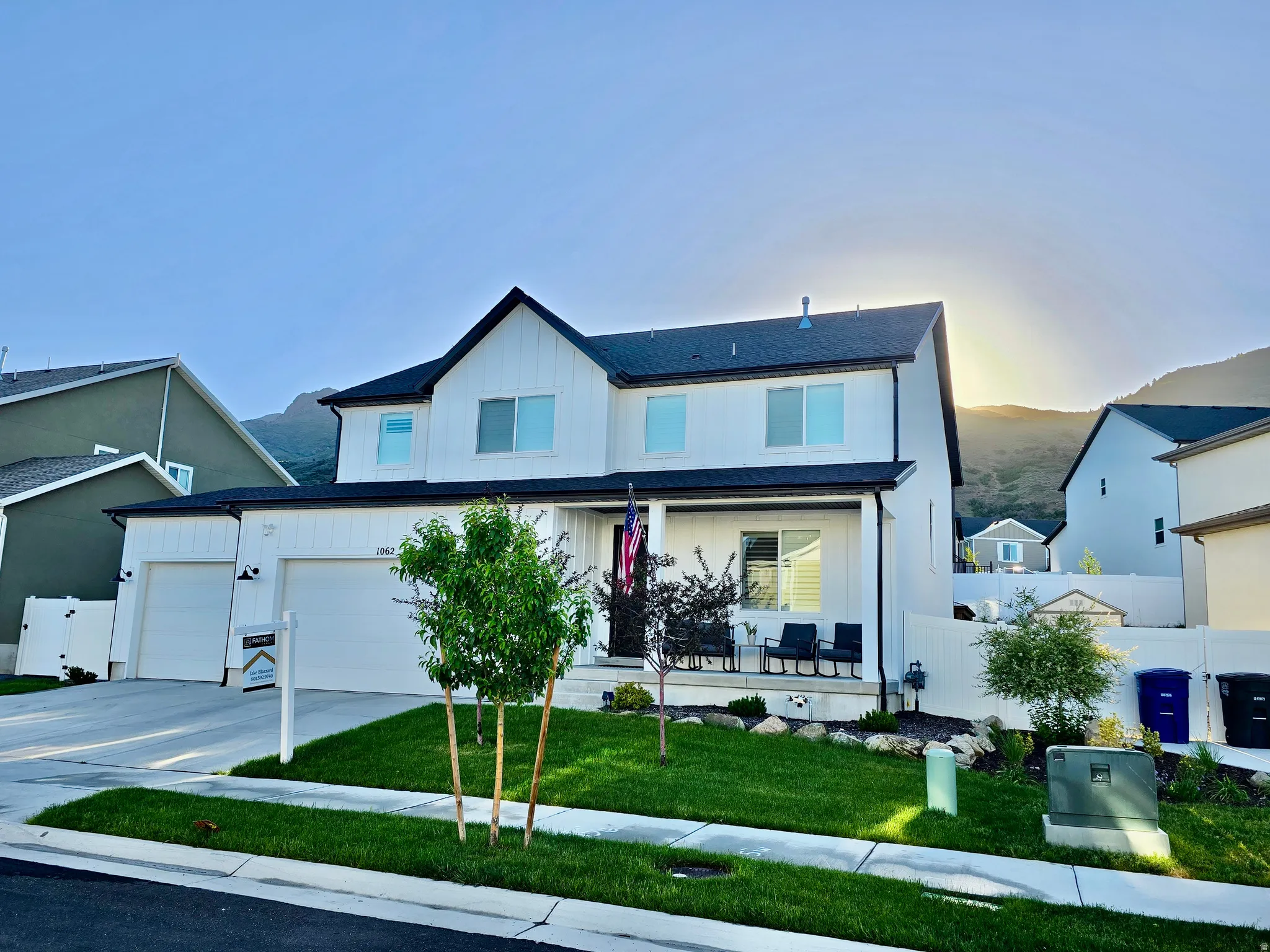 Modern two-story residence featuring a black and white exterior, a three-car garage, and a covered front porch
