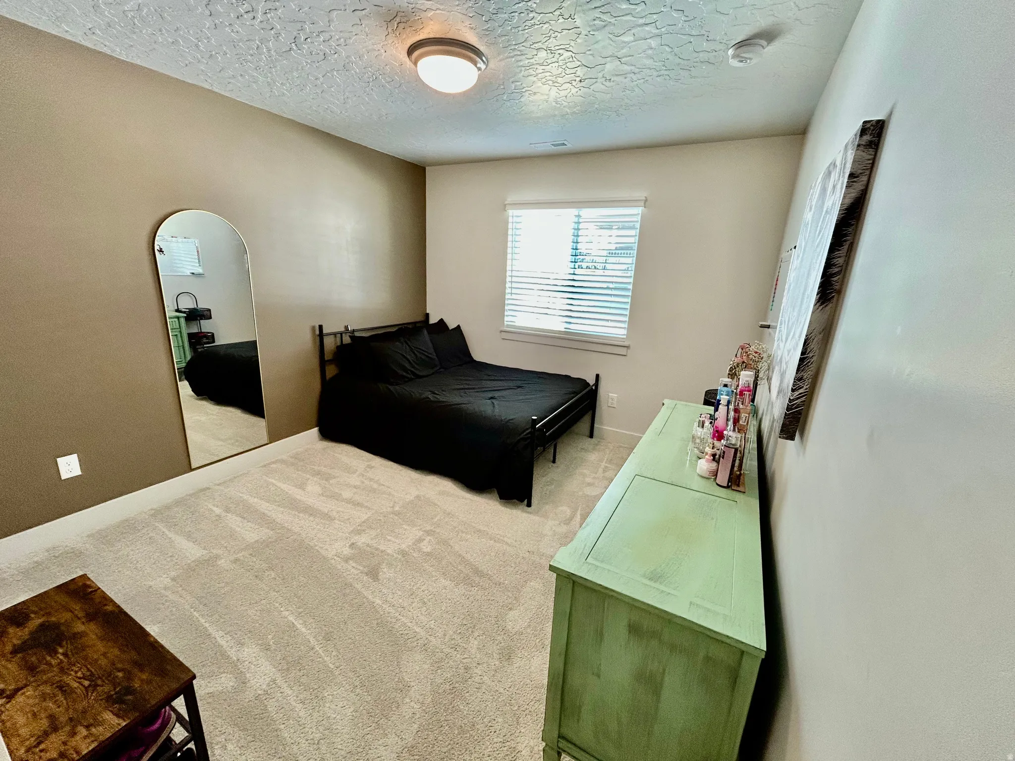 Bedroom with light carpet, arched walkways, and a textured ceiling