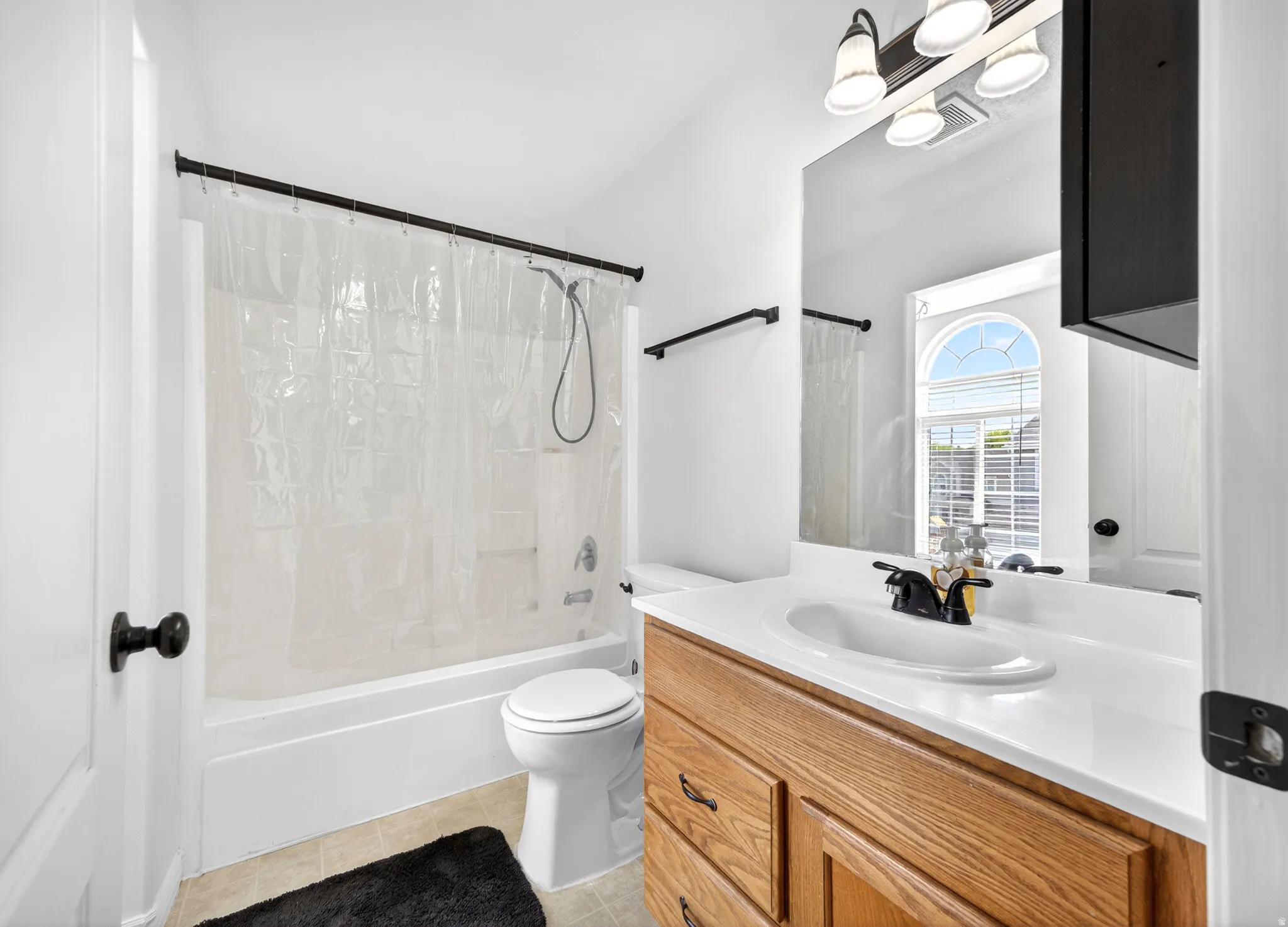 Bathroom featuring vanity, shower / tub combo with curtain, and light tile patterned floors