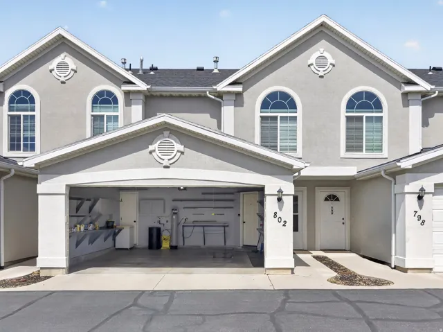 View of front of property featuring stucco siding, a garage, and driveway