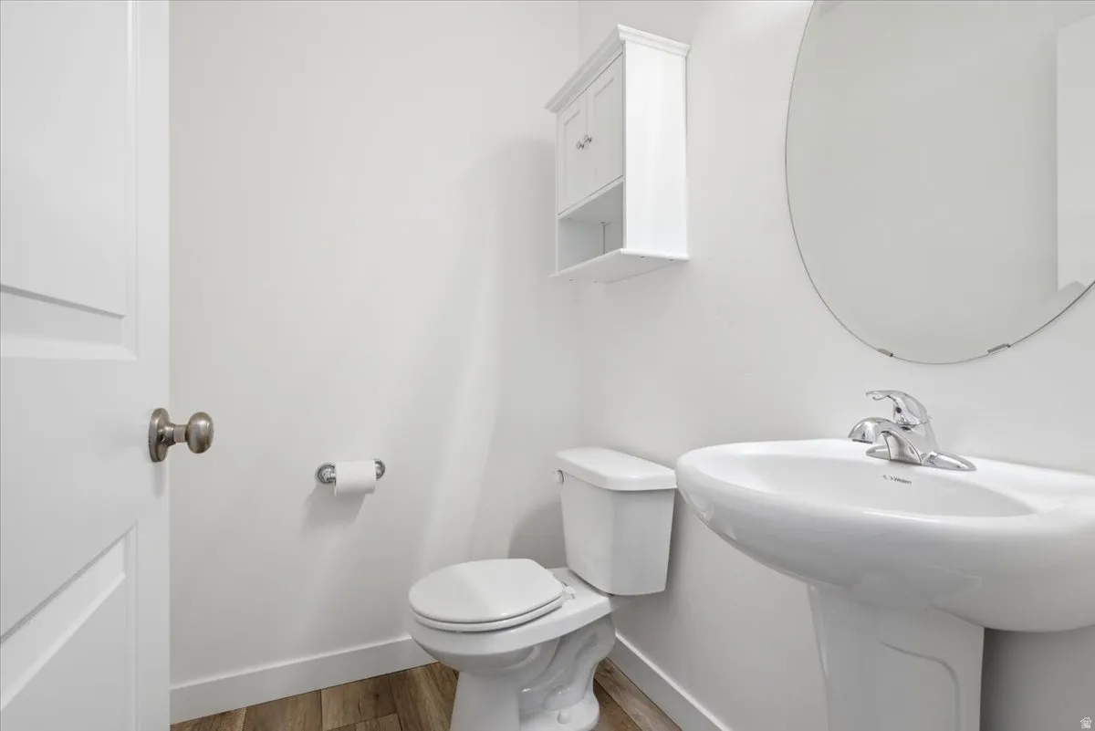 Half bath featuring toilet and light wood finished floors