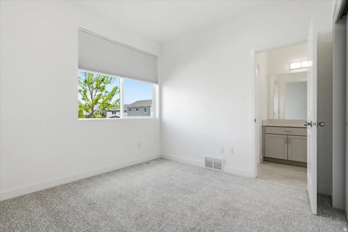 Unfurnished bedroom featuring light carpet and connected bathroom