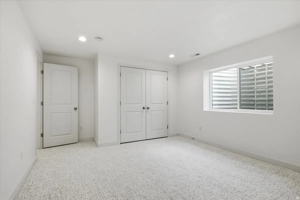 Unfurnished bedroom featuring light colored carpet, a closet, and recessed lighting