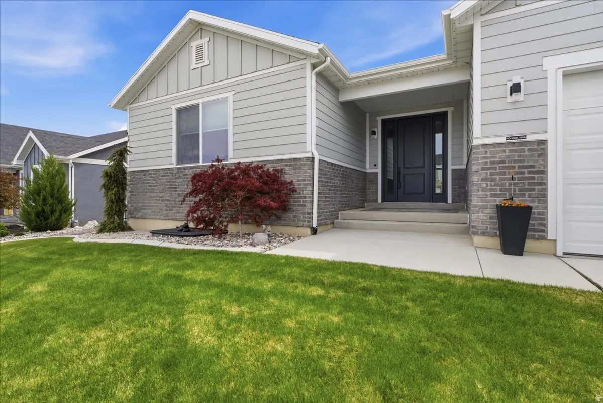 Doorway to property featuring a yard, board and batten siding, and brick siding