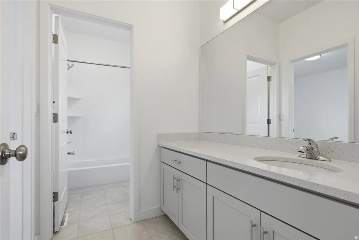 Full bath featuring vanity, shower / bath combination, and light tile patterned floors