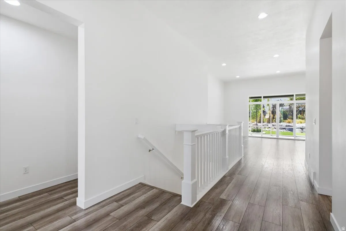Hallway with an upstairs landing, recessed lighting, and dark wood-style floors