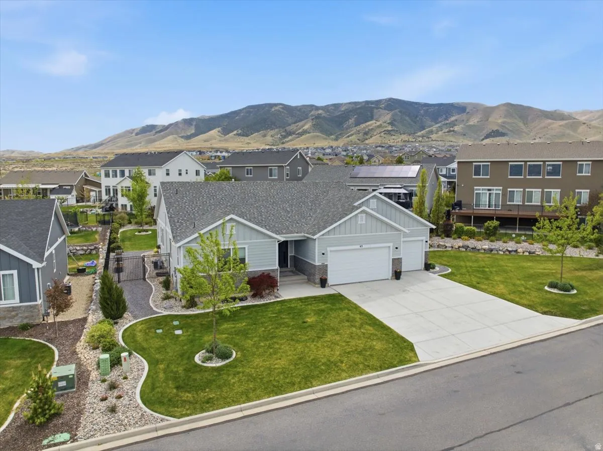 View of front facade featuring board and batten siding, an attached garage, concrete driveway, a mountain view, and a front yard