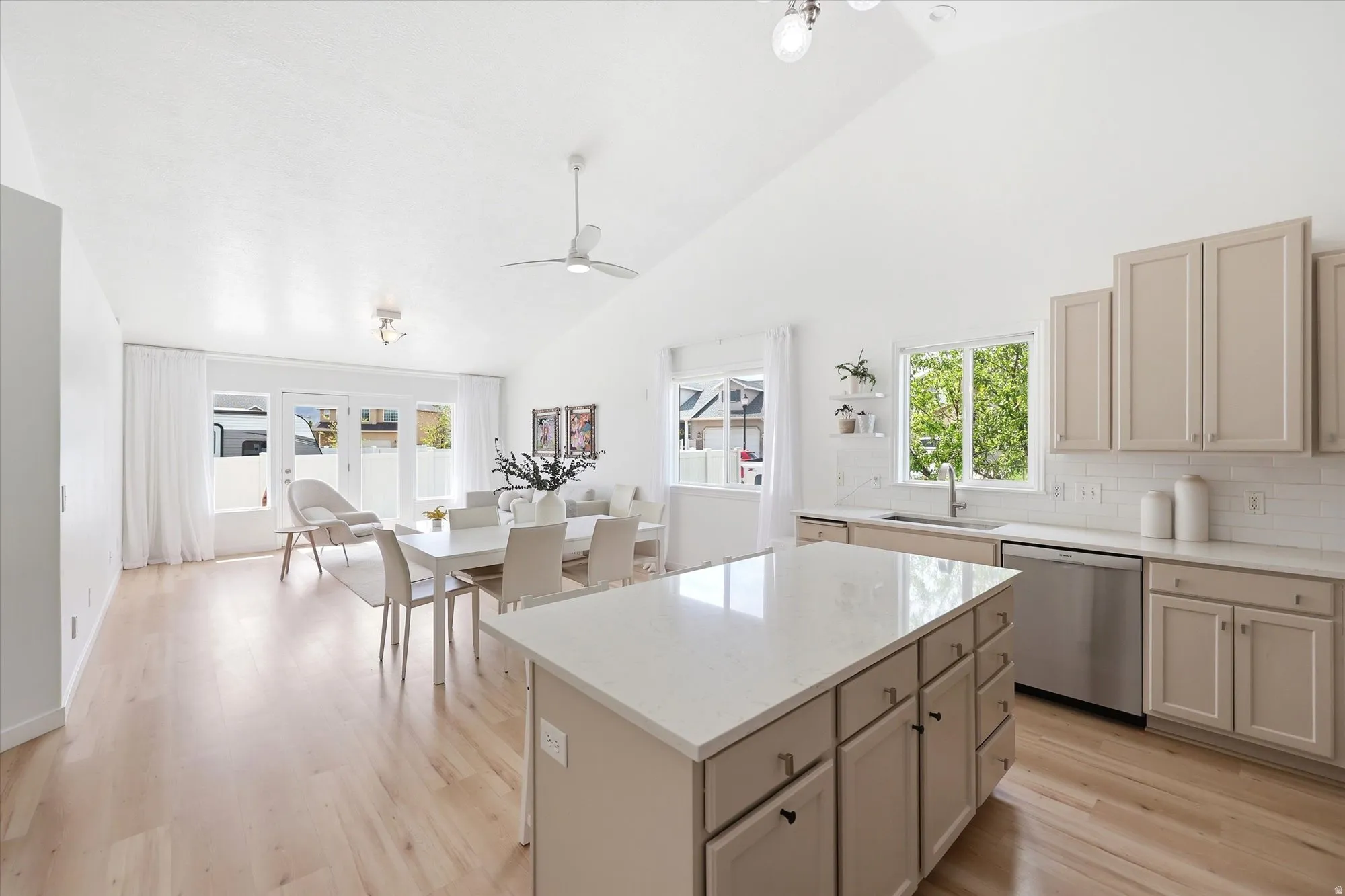 Kitchen with vaulted ceiling, a kitchen island, light wood-style flooring, dishwasher, and decorative backsplash