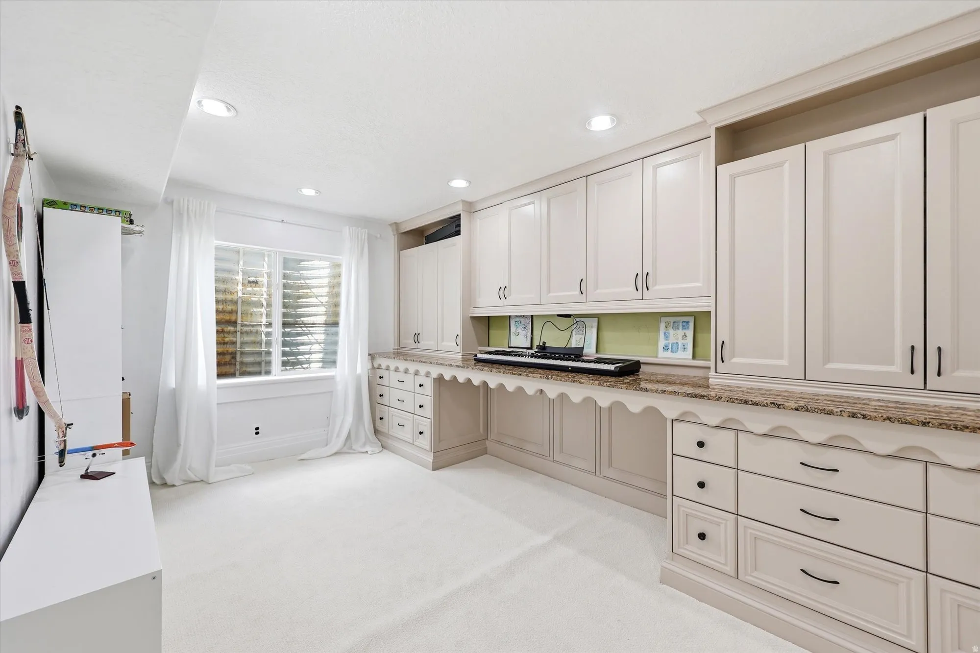 Kitchen with light colored carpet, white cabinets, recessed lighting, and light stone counters