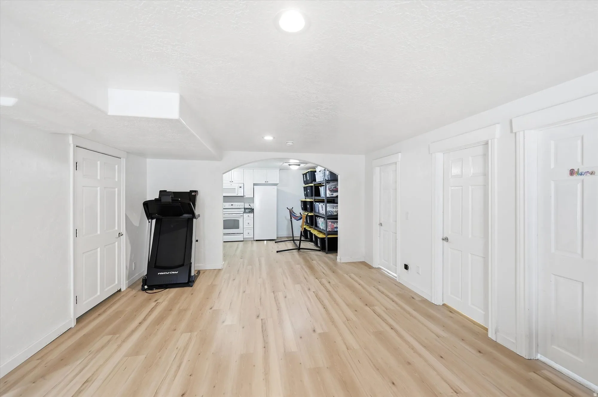 Unfurnished office featuring a textured ceiling, recessed lighting, light wood finished floors, and arched walkways