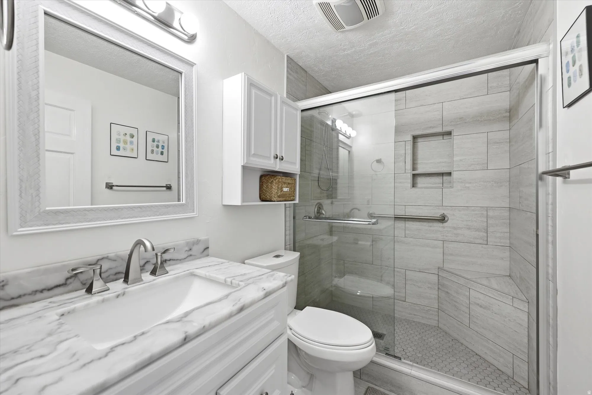 Bathroom with vanity, a shower stall, and a textured ceiling