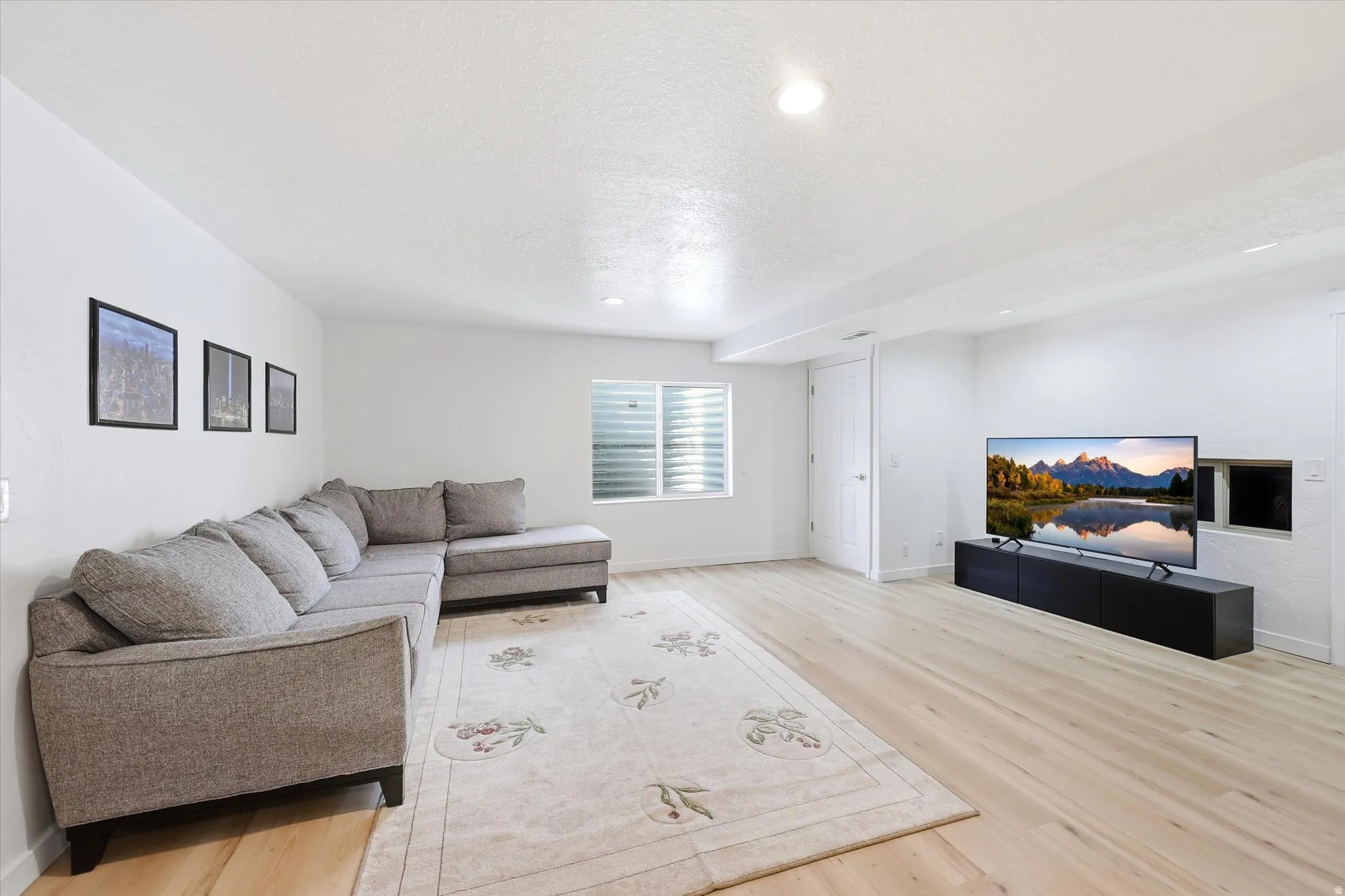 Living area with light wood finished floors, recessed lighting, and a textured ceiling