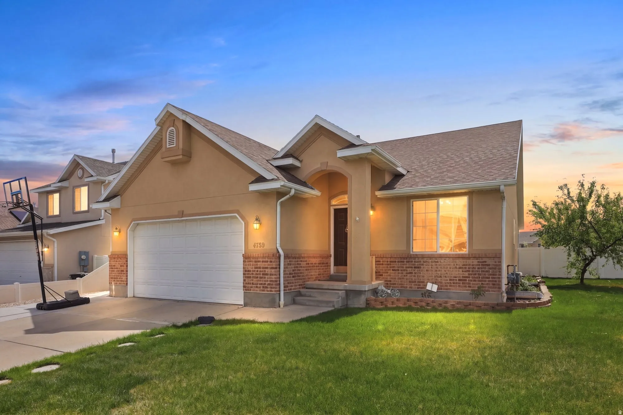 View of front facade with brick siding, an attached garage, stucco siding, and concrete driveway