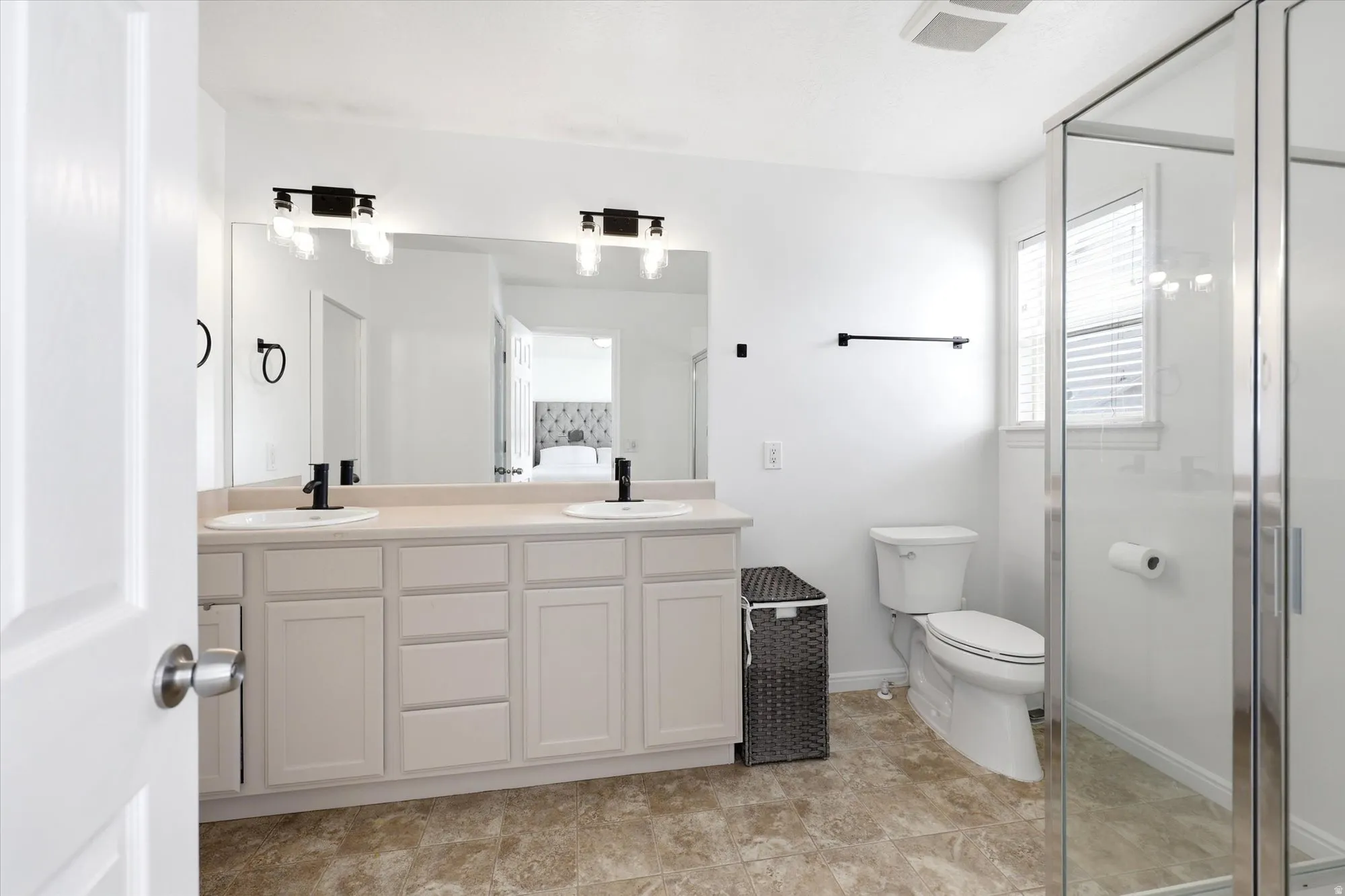 Full bath with double vanity and a shower stall