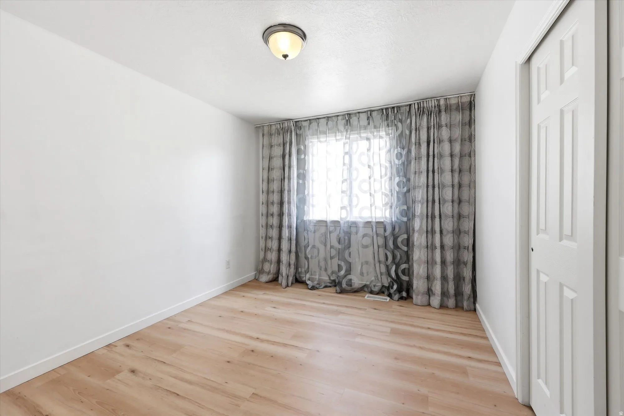 Empty room featuring light wood finished floors and baseboards