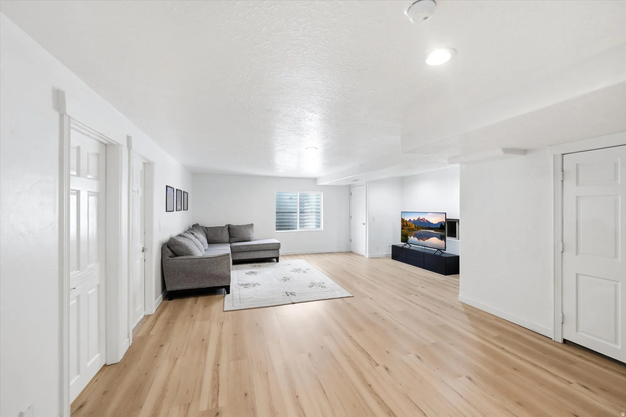 Living room with light wood-type flooring and a textured ceiling