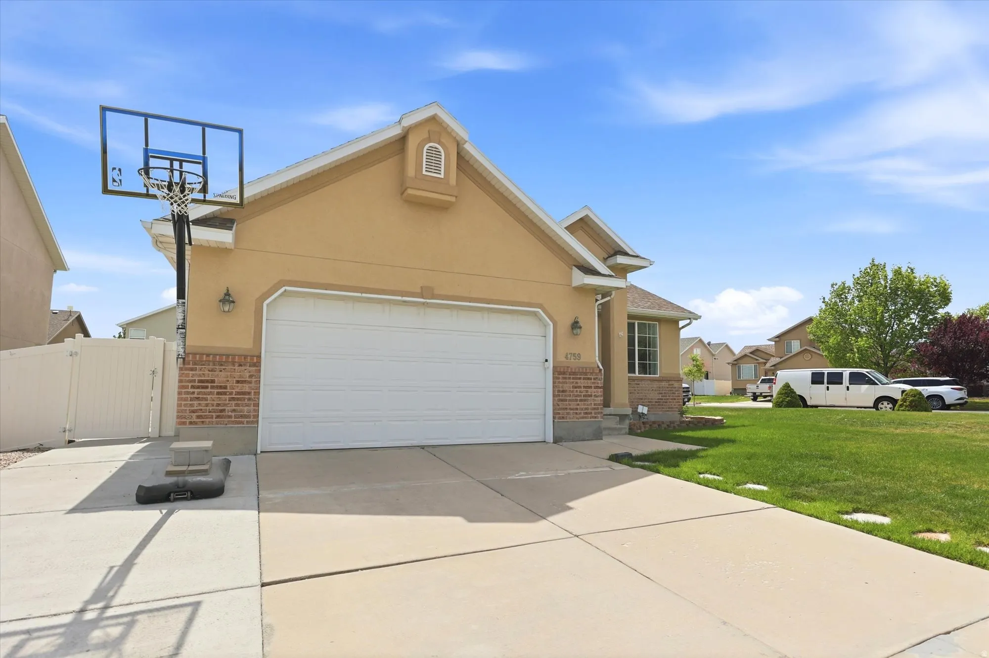 View of front of home with a gate, a garage, stucco siding, brick siding, and driveway
