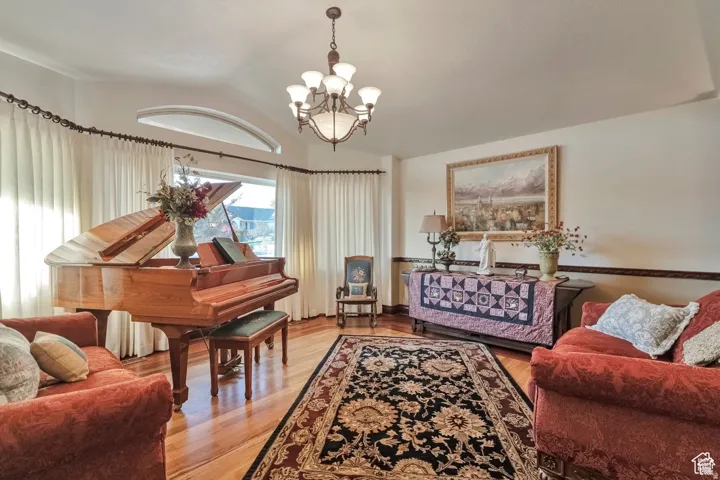 Sitting room featuring light wood finished floors, suspended lighting, and vaulted ceiling