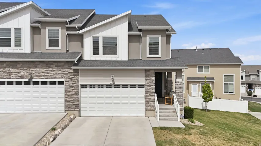 View of front featuring stone and stucco, concrete driveway and green space.