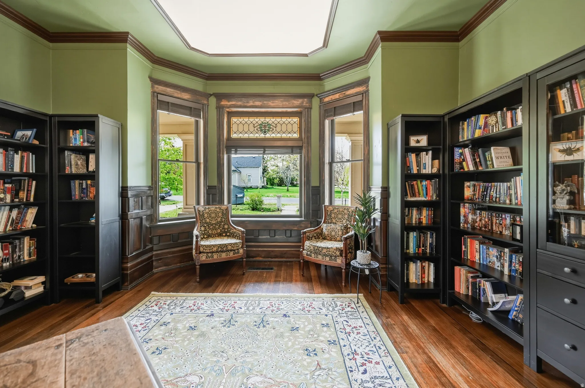 Bay window, dark wood flooring, crown molding & built in book cases