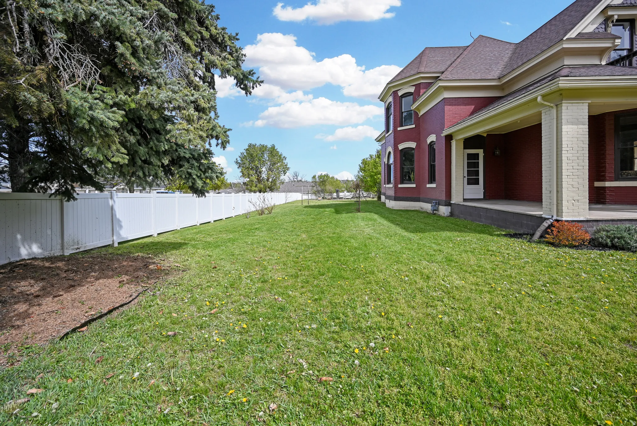 Fenced (west) side-yard featuring covered front porch & front door