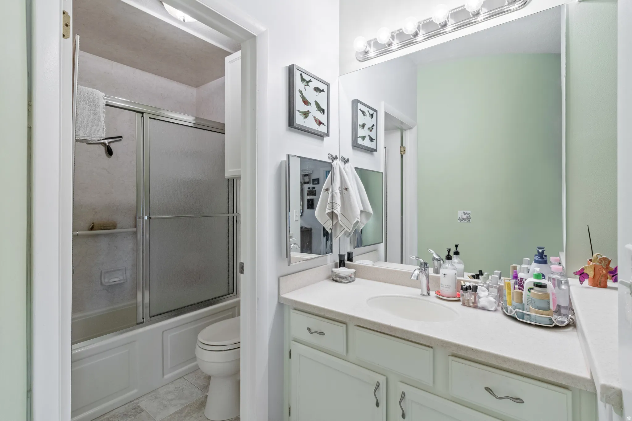 Bathroom featuring vanity and shower / bath combination with glass door
