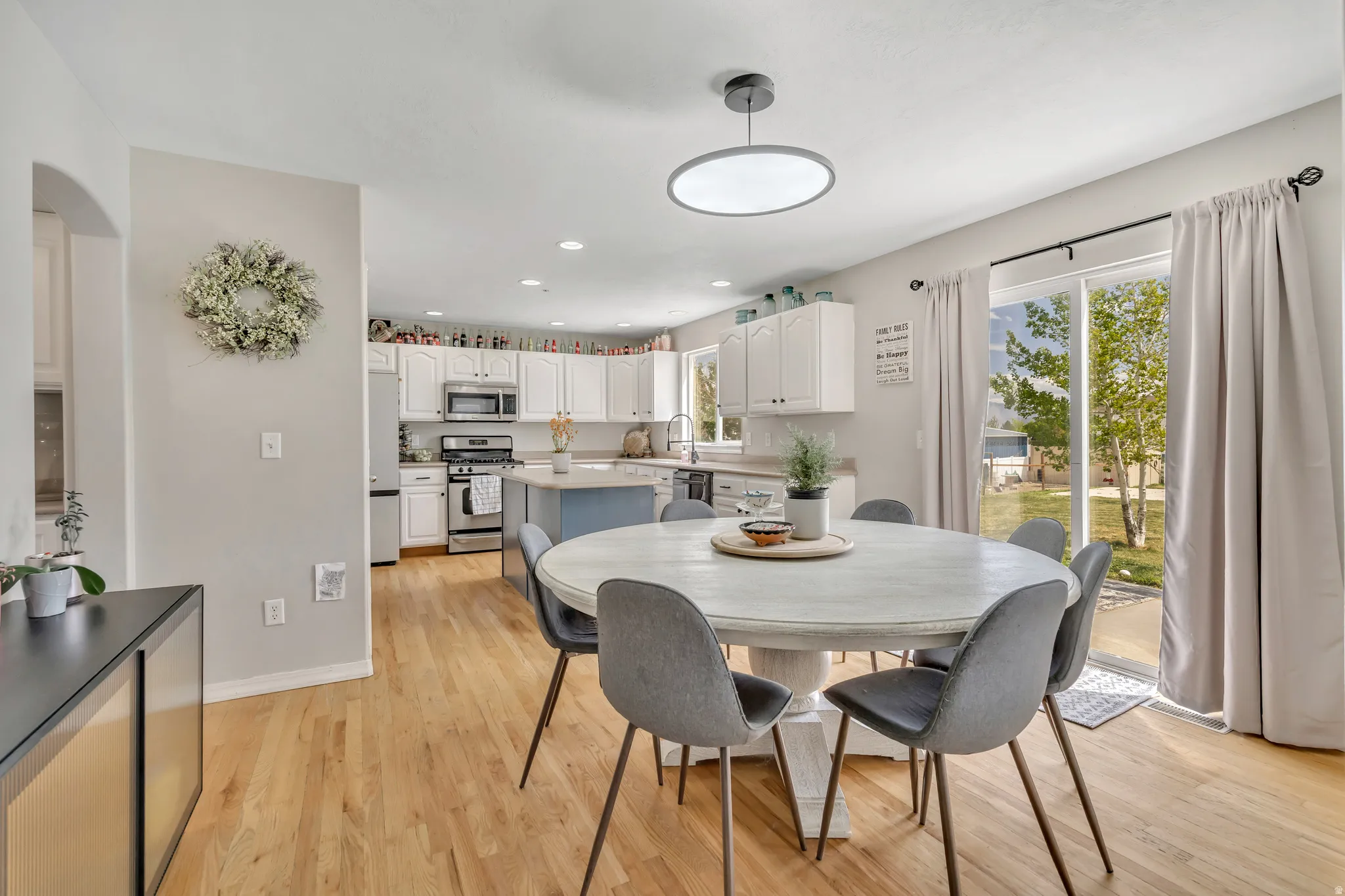 Dining room with light wood-style floors, recessed lighting, and arched walkways