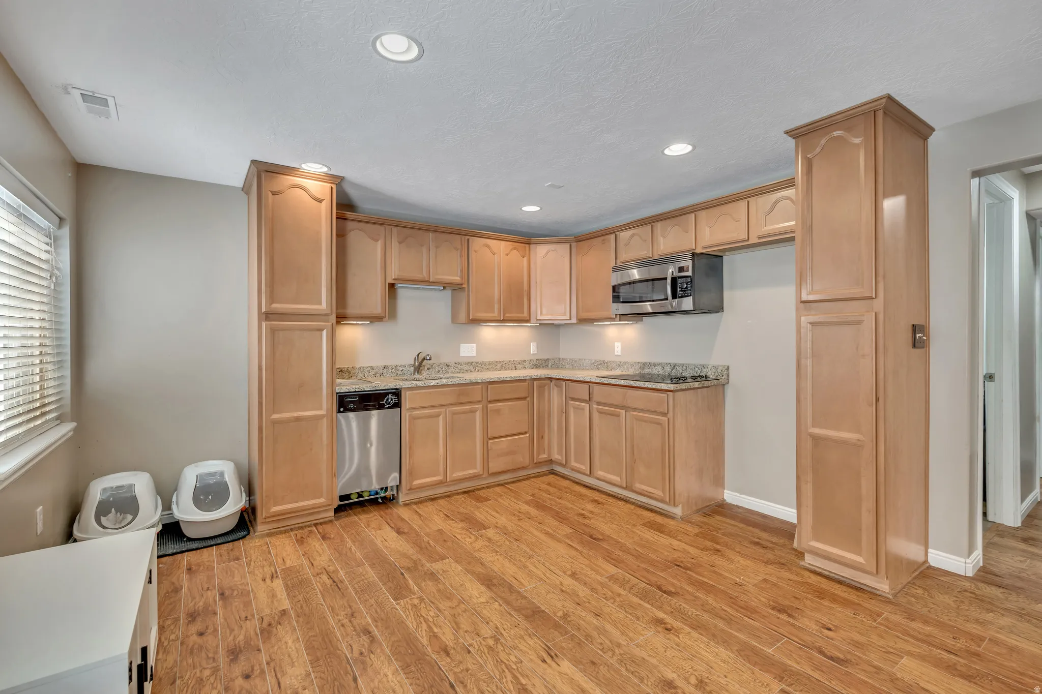 Kitchen featuring stainless steel appliances, light wood-style floors, light wood finish cabinetry, recessed lighting, and light stone countertops