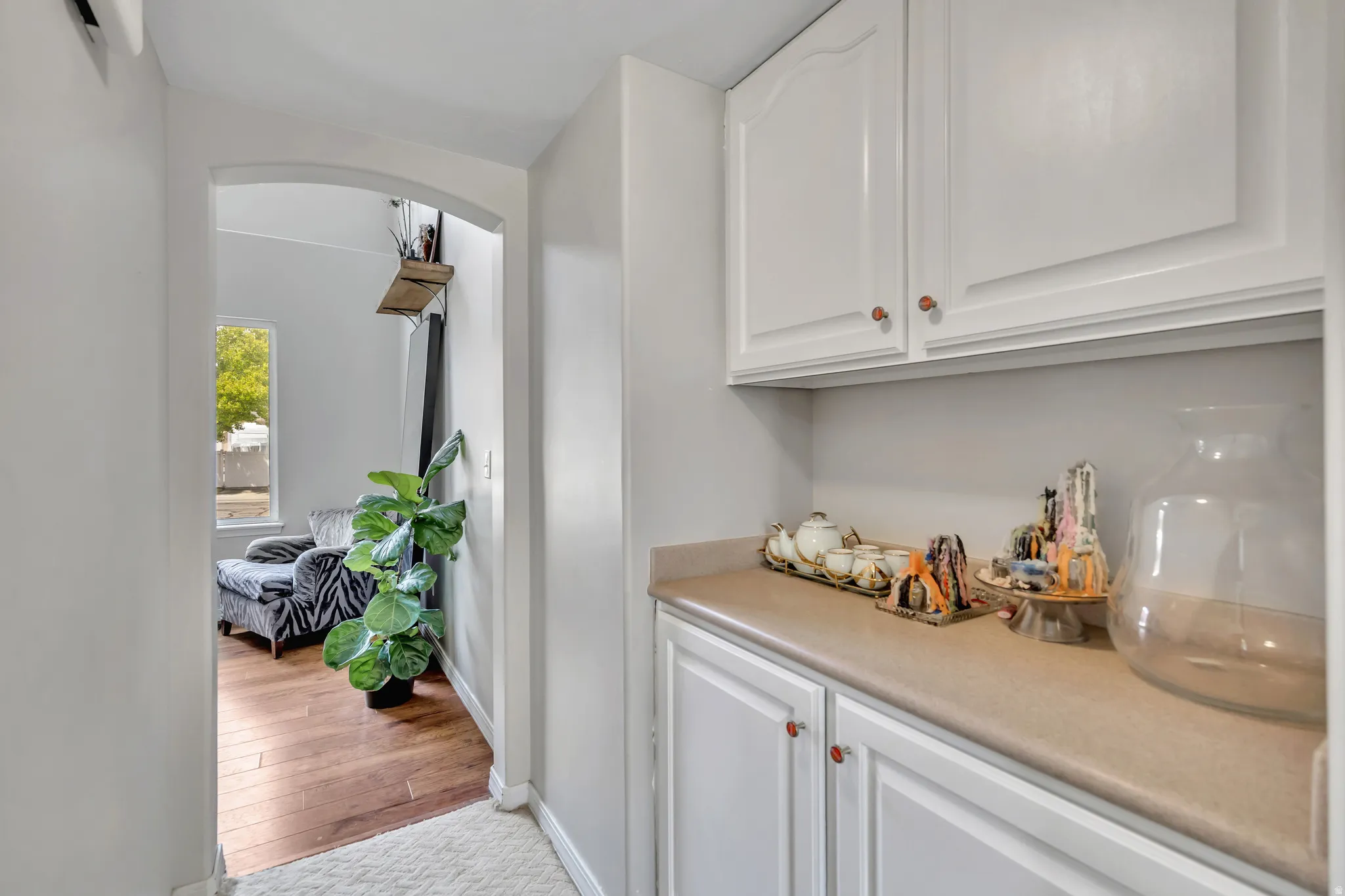 Bar featuring white cabinetry, light countertops, arched walkways, and light wood finished floors