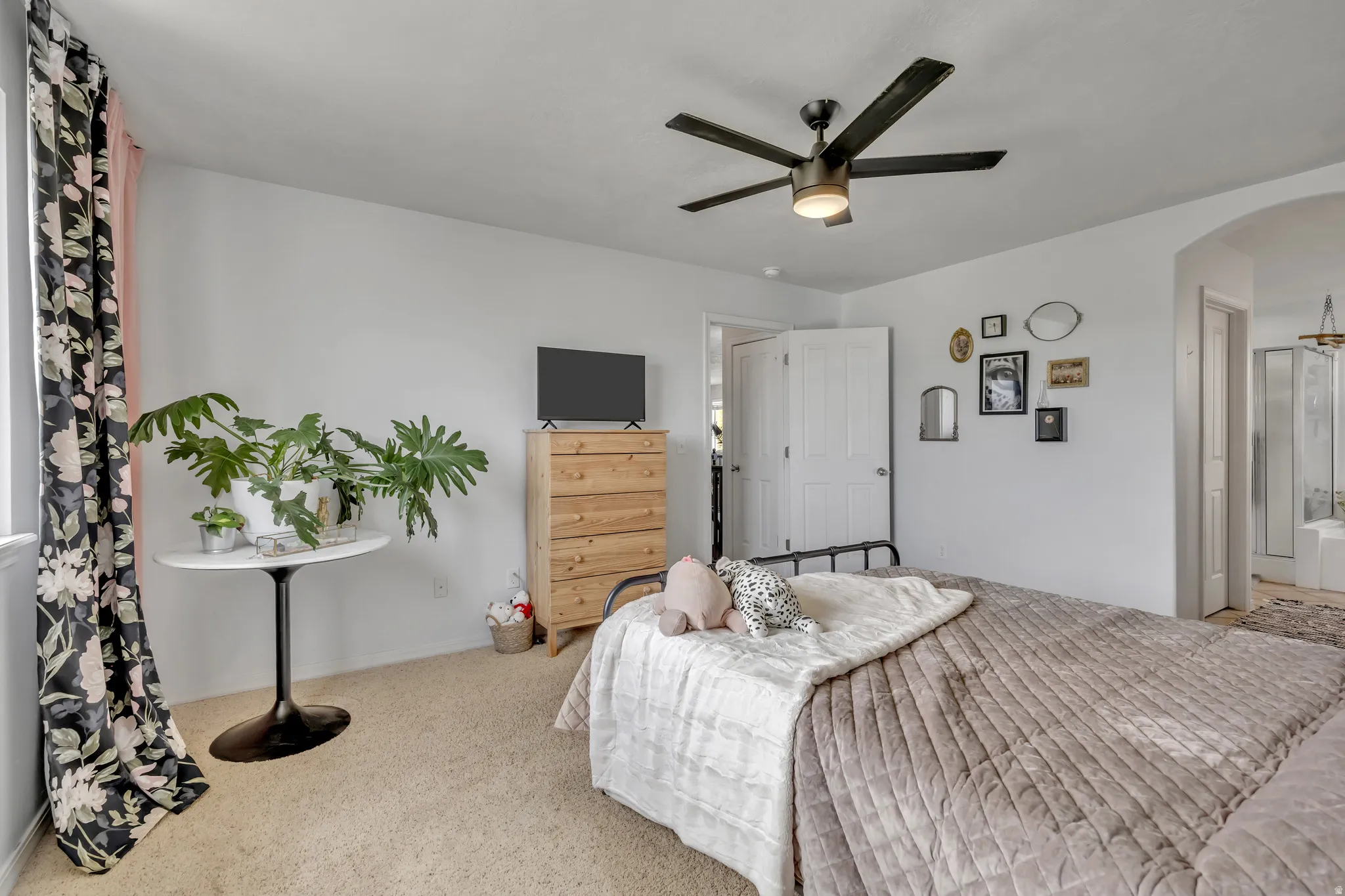 Carpeted bedroom with arched walkways and ceiling fan